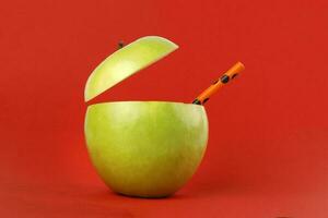 saudável verde cortar maçã reciclável papel Palha suco beber idéia conceito em vermelho fundo foto