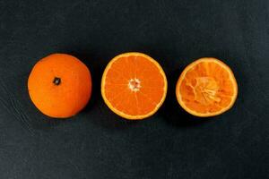 mandarim laranja fruta fatia metade espremido extraído em Preto fundo foto