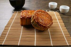 chinês cozido decorado mooncake meio outono festival quadrado volta lua bolo o preenchimento presente desejo oferta em bambu esteira sobre de madeira mesa mini copo foto