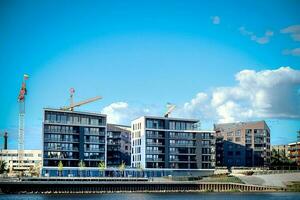 moderno residencial edifícios em a rio banco em azul céu fundo com nuvens em uma caloroso verão dia foto