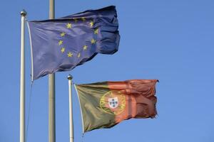 Português nacional bandeira e bandeira do a europeu União acenando dentro a vento foto