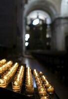 muitas pequenas velas iluminando uma sala escura da igreja foto