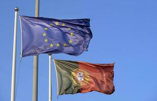 Português nacional bandeira e bandeira do a europeu União acenando dentro a vento foto