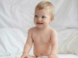 fofa bebê sentado e sorridente em a cama foto