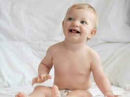 fofa bebê sentado e sorridente em a cama foto