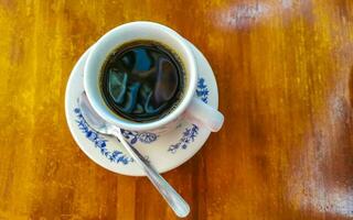 pote de xícara branca azul com mesa de madeira de café preto méxico. foto