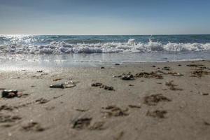 surfe na praia com luz de fundo com ondas, conchas de areia e águas-vivas foto