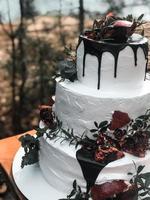 lindo bolo de casamento de creme branco de três camadas com frutas de romã e flores frescas foto