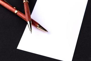 caneta de luxo e lapiseira em madeira e ouro com uma folha de papel branca foto