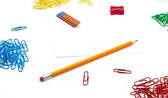 lápis, borracha, apontador e clipes de papel em um fundo branco foto