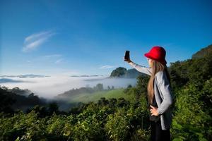 mulher tirando foto de selfie na montanha com névoa ao fundo, paisagem na província de mae hong son, Tailândia