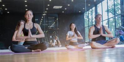 grupo fazendo ioga na academia por meio de alongamento, conceito de exercício saudável foto