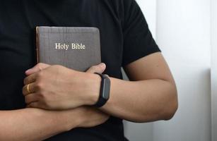 um homem está segurando e abraçando uma bíblia pela manhã foto
