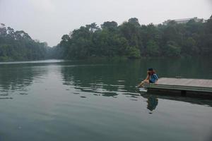 menina sentada perto do lago foto