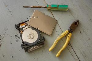 disco rígido quebrado e destruído e ferramentas na mesa de madeira foto