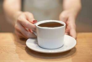 fêmea mão servir uma copo do café para cliente às a café fazer compras. foto