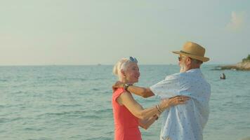 dois idosos homens e mulheres dançando às a de praia em seus verão período de férias e elas sorrir e apreciar seus dia desligado. foto