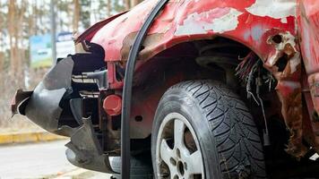 quebrado amarrotado vermelho carro depois de uma forte acidente com uma enviesado corpo, depois de uma poderoso soprar. acidente em a rua, estragado carro depois de uma colisão dentro a cidade. auto acidente. quebrado carro em a rua. foto