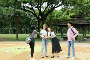 jovem ásia malaio chinês homem mulher ao ar livre parque livro Arquivo pasta computador portátil computador telefone sentar ficar de pé estude misturar-se foto