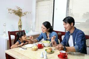 sul leste ásia Yong família filha criança pai pai mãe às jantar mesa comendo Comida almoço foto