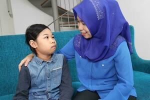 sudeste ásia malaio mãe filha sentar em azul sofá falar. mãe é adhd e criança autismo autista foto