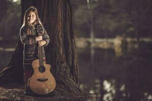 menina com guitarra dentro a parque foto