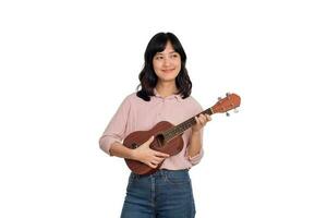 feliz jovem ásia mulher com casual roupas jogando ukulele isolado em branco fundo foto