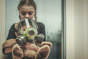 menina segurando e protegendo Urso de pelúcia Urso com gás mascarar. foto