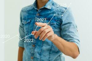 do homem mão apontando gráfico do sucesso dentro 2023 ano. crescendo o negócio conceito foto