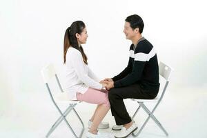 sul leste ásia jovem chinês casal marido esposa feliz amor sentar em branco cadeira branco fundo face para face segurando mão foto