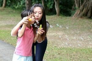 sul leste ásia jovem chinês mãe filha pai criança jogando com Sabonete bolhas relaxar atividade ao ar livre parque foto