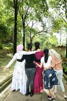 grupo do mulher malaio chinês indiano ásia ao ar livre verde parque andar mão em ombro juntos unidade foto