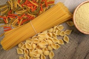 seco cru espaguete Conchiglie conchas do mar fusilli cortiça parafuso cor massa cuscuz variedade em rústico madeira fundo foto