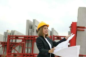 ásia mulher chinês malaio trabalhador engenheiro gestão Difícil chapéu segurança capacete às construção local lendo vendo plano projeto foto