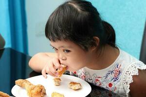 pequeno sul leste ásia menina comendo almoço sentado às jantar mesa. ela ter baixa síndrome foto