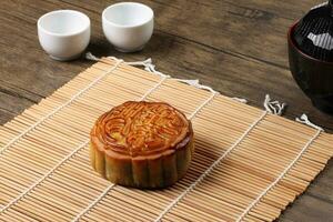 chinês cozido decorado mooncake meio outono festival volta lua bolo o preenchimento presente desejo oferta em bambu esteira sobre de madeira mesa mini copo foto