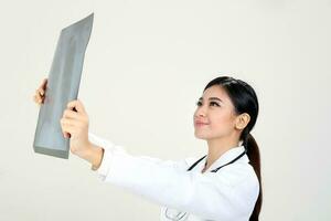 jovem ásia fêmea médico vestindo avental estetoscópio segurando olhando x raio foto