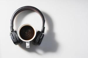 fones de ouvido e xícara de café no fundo branco foto