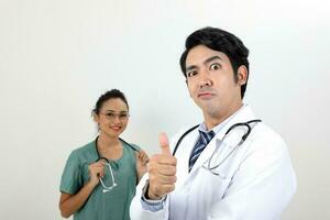 jovem ásia malaio chinês masculino fêmea médico em branco fundo polegares acima engraçado face às Câmera foto