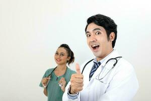 jovem ásia malaio chinês masculino fêmea médico em branco fundo polegares acima feliz face às Câmera foto