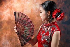 sul leste ásia chinês raça étnico origem mulher vestindo vermelho veludo cheongsam com mão costurado seqüência trabalhos vestir traje mão ventilador em retro vintage fundo foto