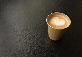 xícara de café artesanal com formato de coração copie espaço em uma mesa preta texturizada foto
