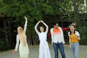 grupo jovem ásia chinês malaio homem mulher vestindo lenço de cabeça ao ar livre feliz dança mão dentro a ar conversa disco amigo aluna colega feliz saiu foto