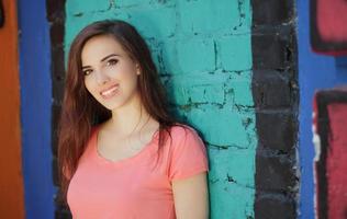 garota sorridente com cabelo castanho perto de uma parede colorida foto
