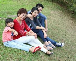 sudeste ásia multigeração família pais filha avó pai mãe criança pose feliz sentar ficar de pé ao ar livre parque foto