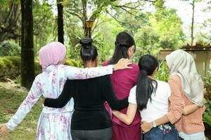 grupo do mulher malaio chinês indiano ásia ao ar livre verde parque andar mão em ombro cintura juntos unidade foto