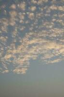 tarde altocumulus nuvens gostar uma rebanho do cavalinha e uma rebanho do ovelha flutuando dentro uma lindo céu dentro uma rural área dentro tailândia, quando a Sol tem definir, isto é uma panorâmico Visão do cordialidade, romance, Paz foto