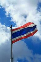 a tailandês bandeira este é estourado longe de a vento com a azul céu fundo e nuvens dentro a meio do a quente Sol e Forte vento. foto
