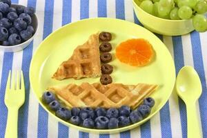 criativo idéia para crianças café da manhã. barco do waffles com amoras e tangerinas. foto