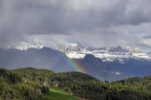 chuva forte com arco-íris nas altas montanhas nevadas foto